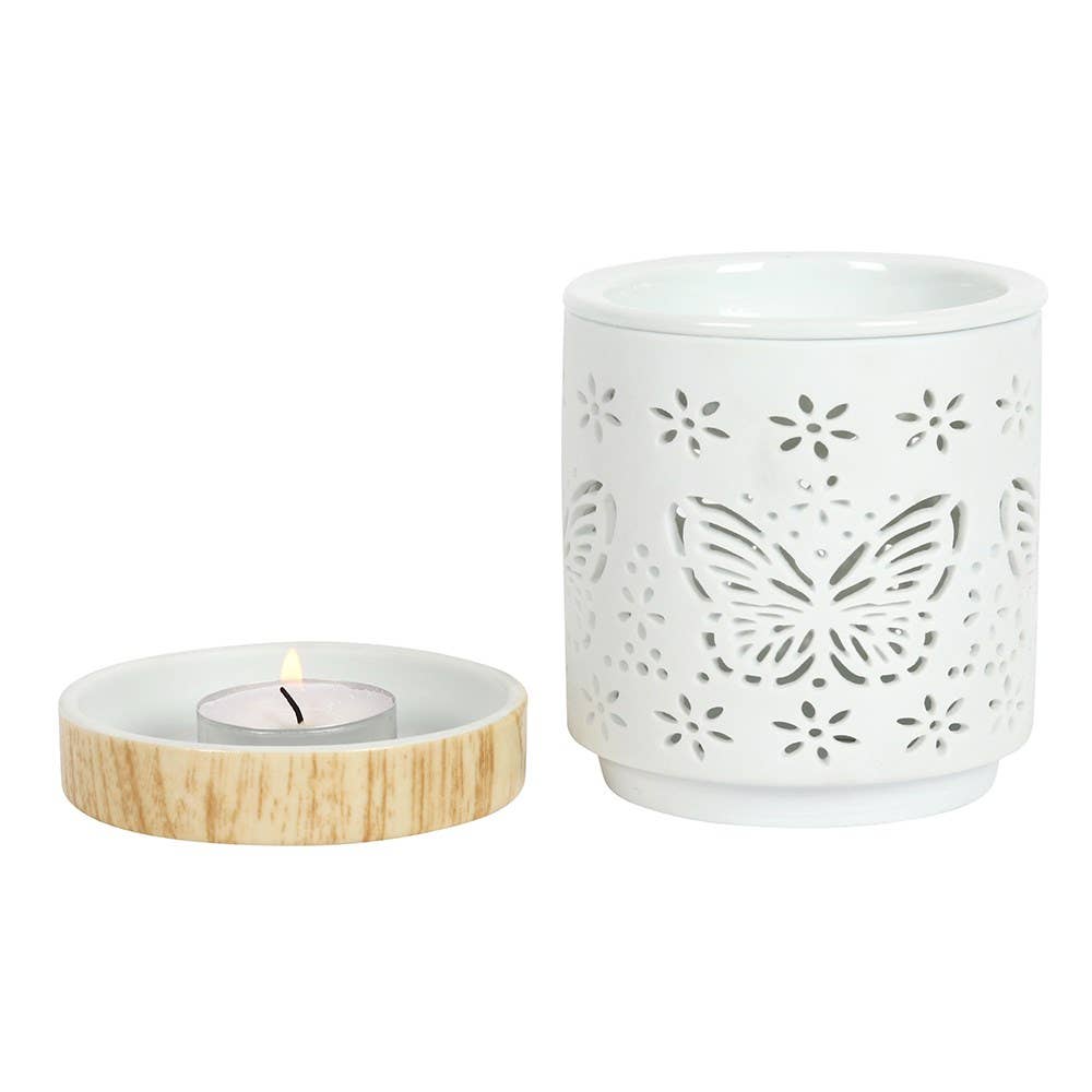 White ceramic container with butterfly design and wooden candle holder on a white background