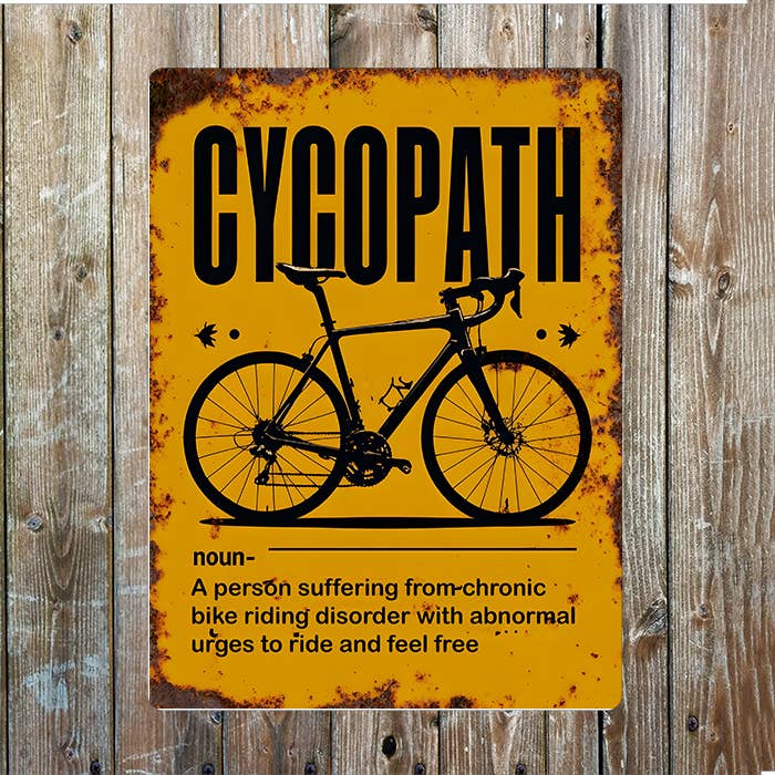 Metal sign with a bicycle graphic and text on a wooden background