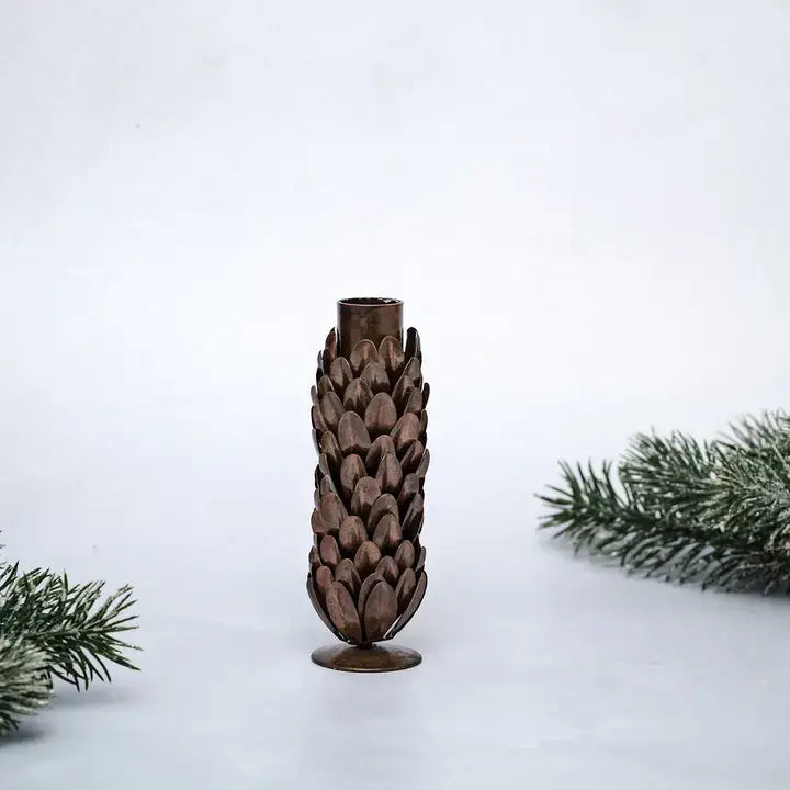 Decorative candle holder shaped like a pine cone on a white background with pine branches.