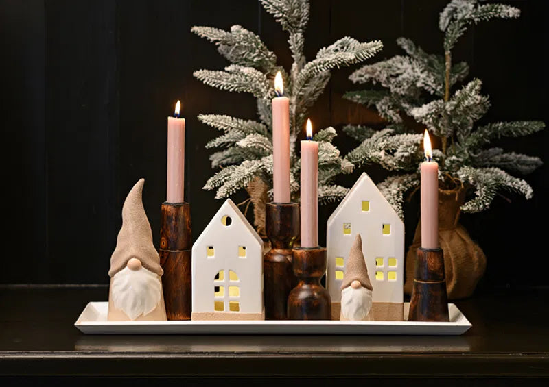 Decorative setup with gnome figurines, candle holders, and a small tree on a dark background