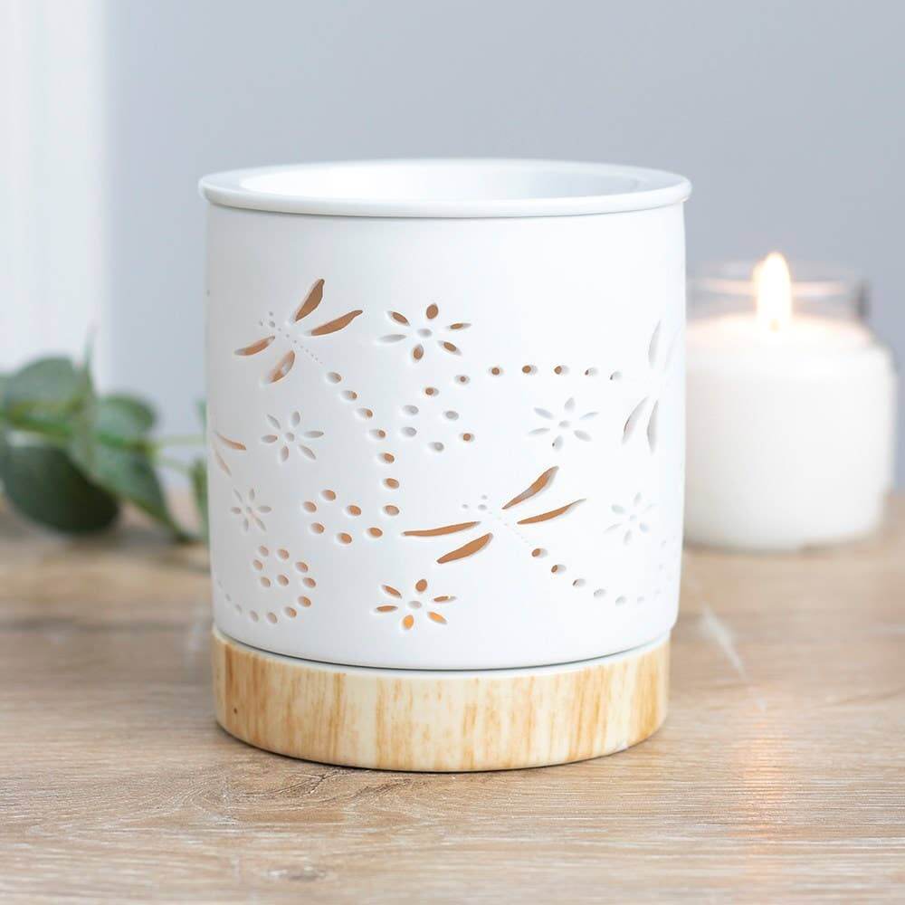 White ceramic lantern with wooden base on a wooden surface, with a blurred candle in the background.