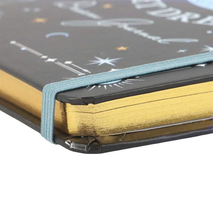 Close-up of a notebook with a black cover featuring celestial designs and gold edges.