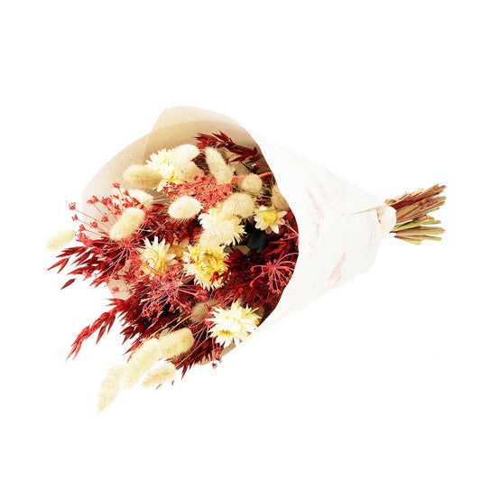 A dried flower bouquet featuring a mix of red and white flowers, including oats and lagurus, wrapped in a paper bundle.