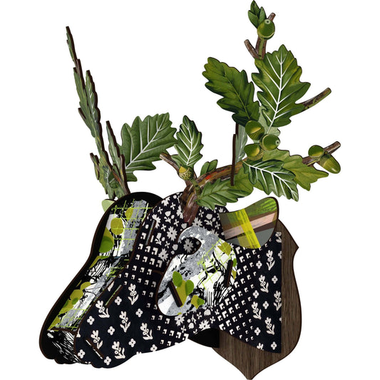 A decorative stag head wall art with a floral pattern in black, white, and green, featuring branch, oak leaf, and acorn effects.