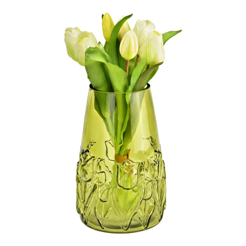 Green glass vase with decorative patterns containing white tulips on a white background