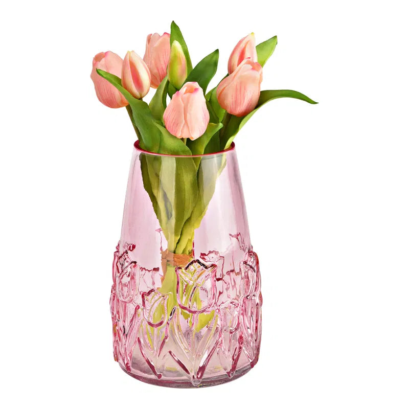 Pink glass vase with floral design containing pink tulips on a white background