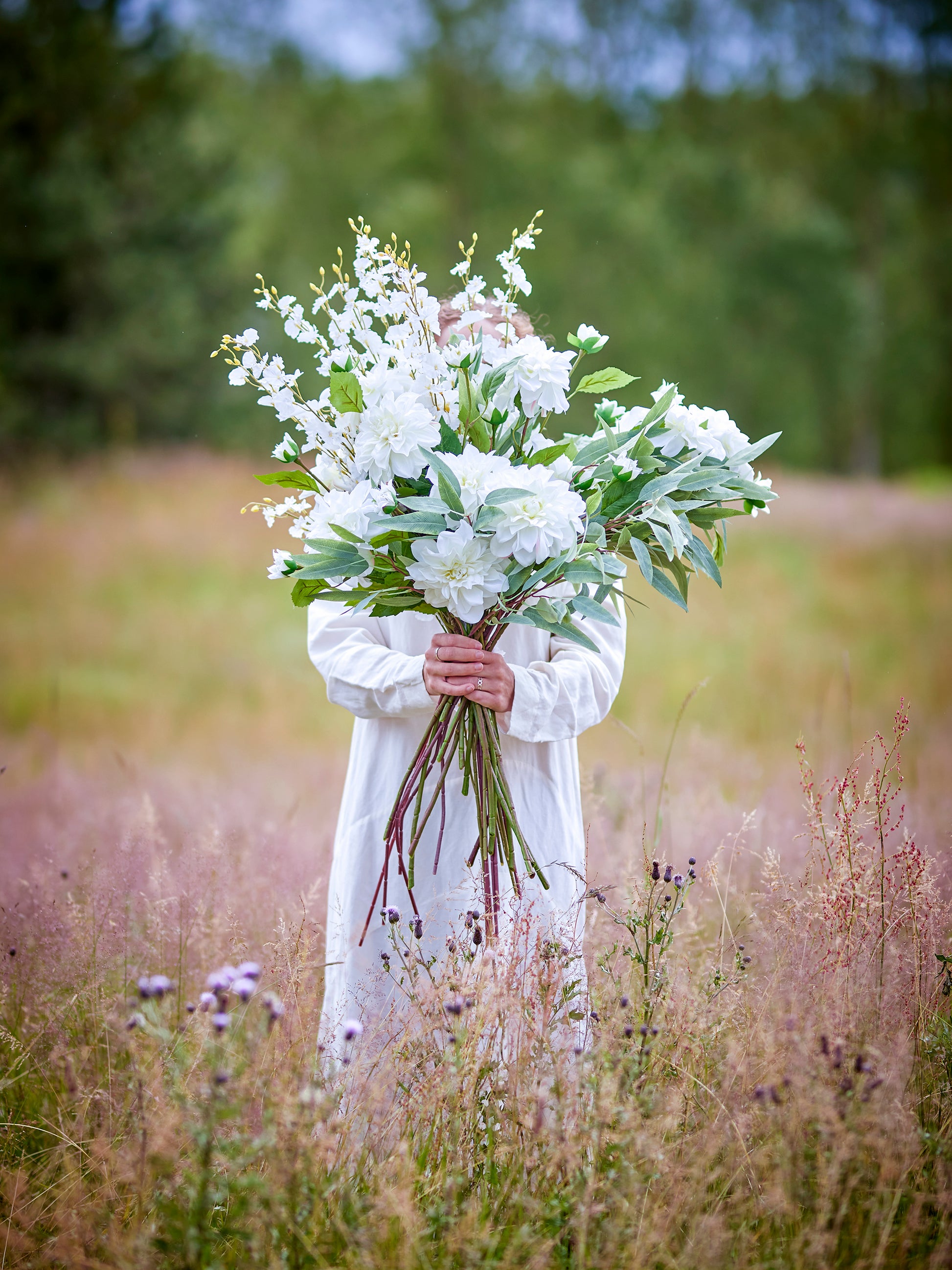 Person holding a bouquet of white flowers in a field