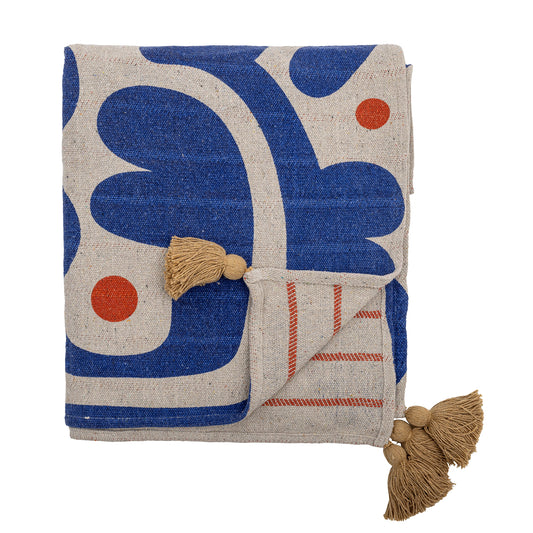 A recycled cotton blanket with a blue and red pattern on one side and bold woven red stripes on the other, featuring yellow tassels at each corner.