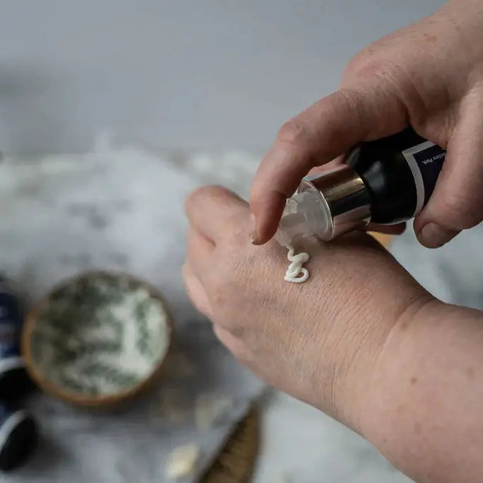 Hand applying a skincare product to the wrist with a blurred background