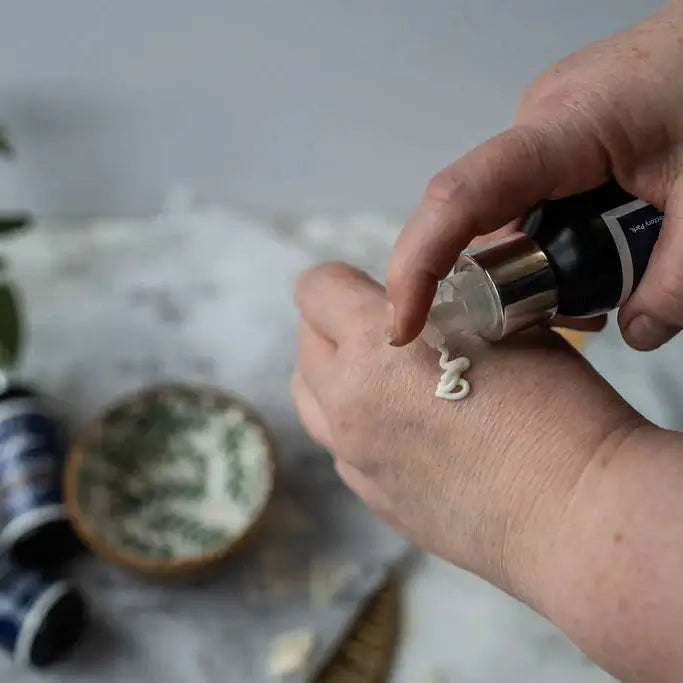 Hand applying a skincare product to the wrist with a blurred background