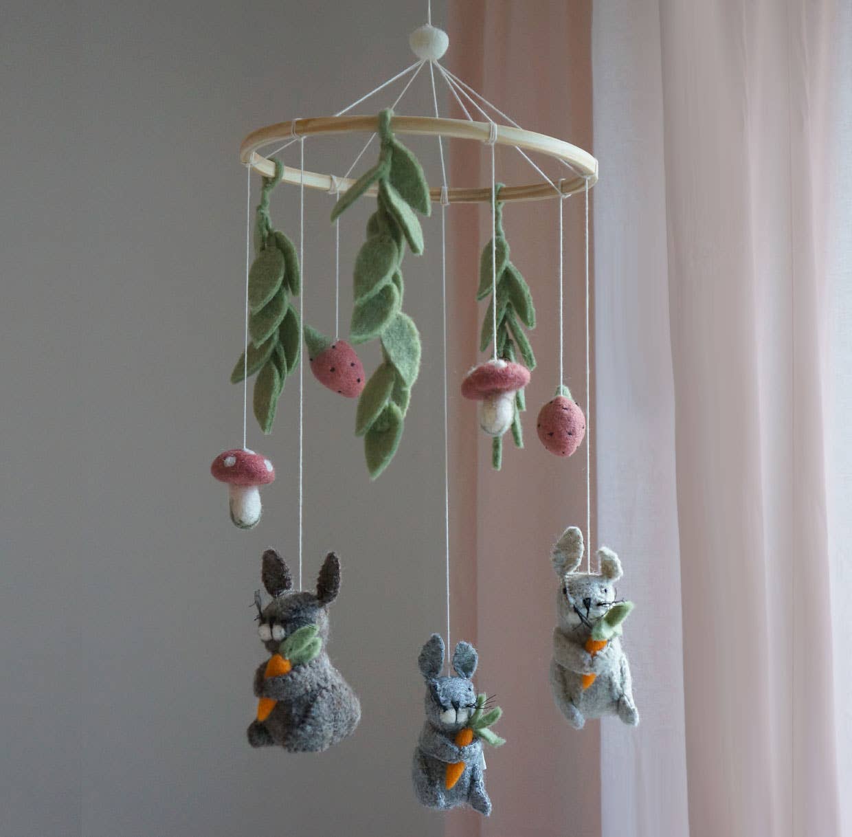 Children's mobile with hanging plush animals and leaves on a plain background