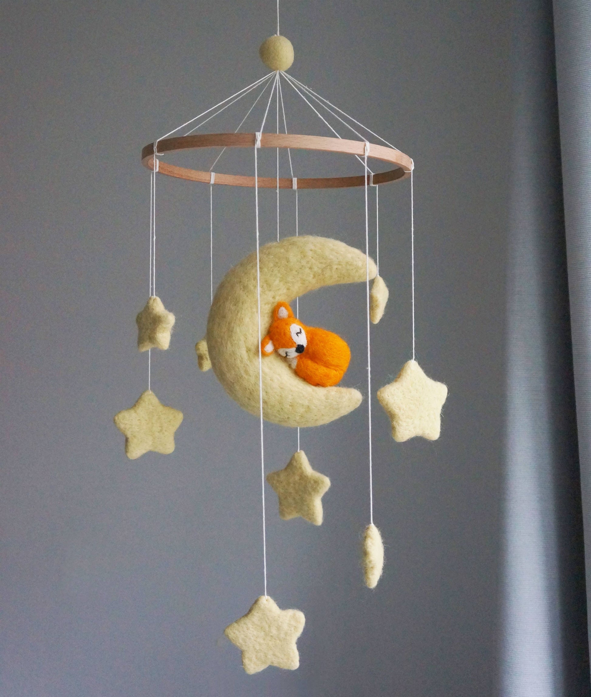 Baby mobile with moon, stars, and a fox toy against a gray background
