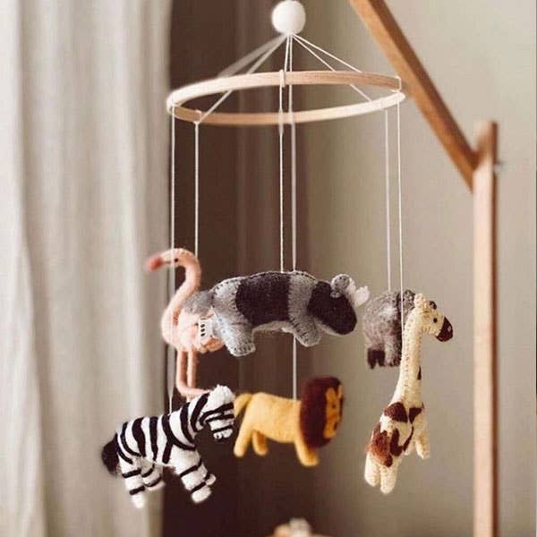 Baby mobile with animal toys hanging from a wooden ring against a neutral background