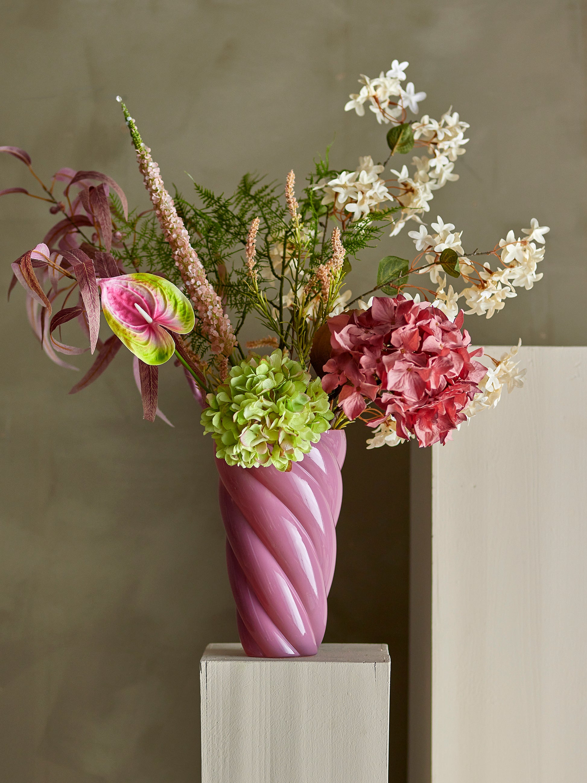 Purple vase with a bouquet of flowers on a neutral background