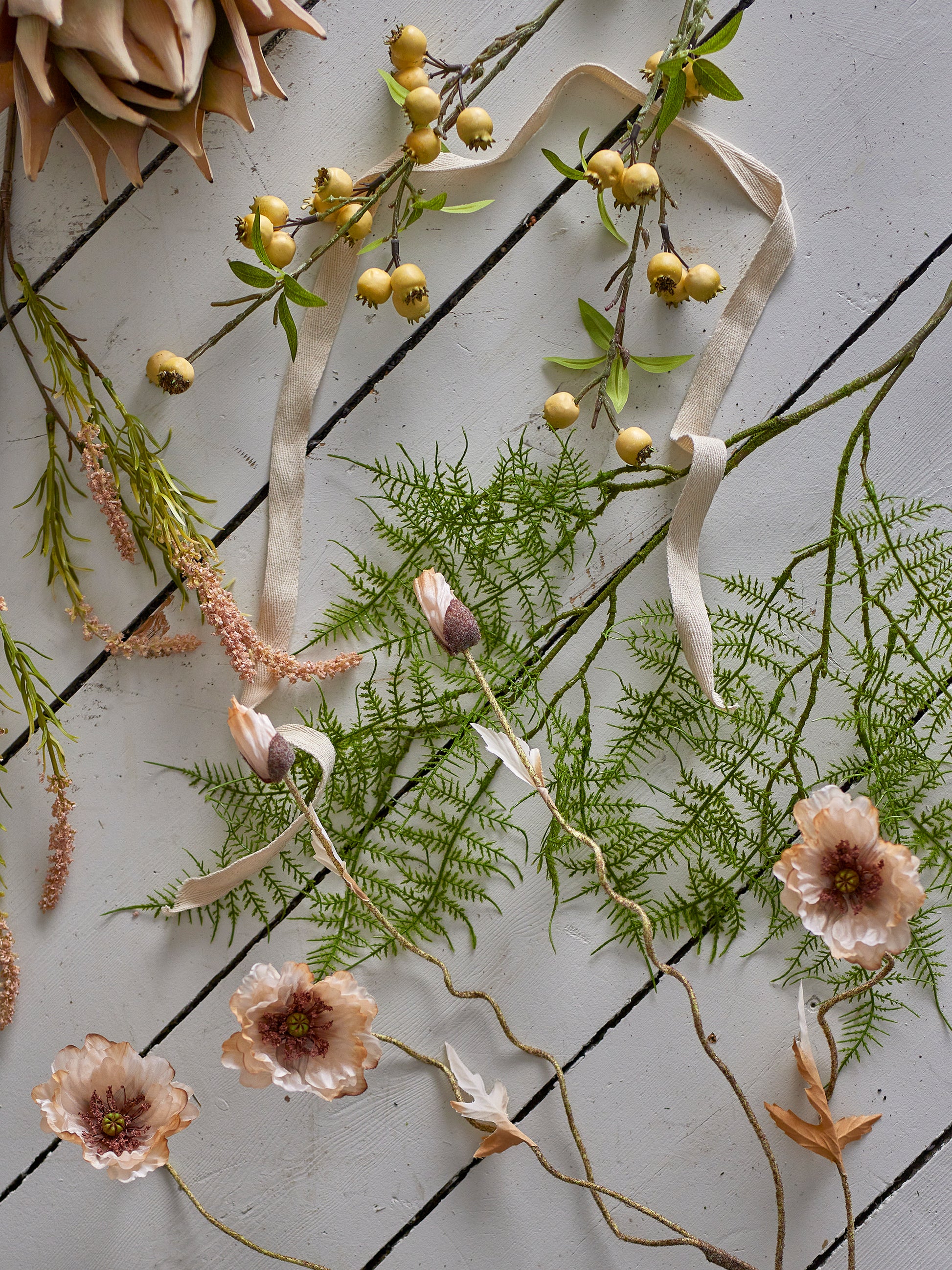 Decorative arrangement of greenery, flowers, and ribbons on a textured surface