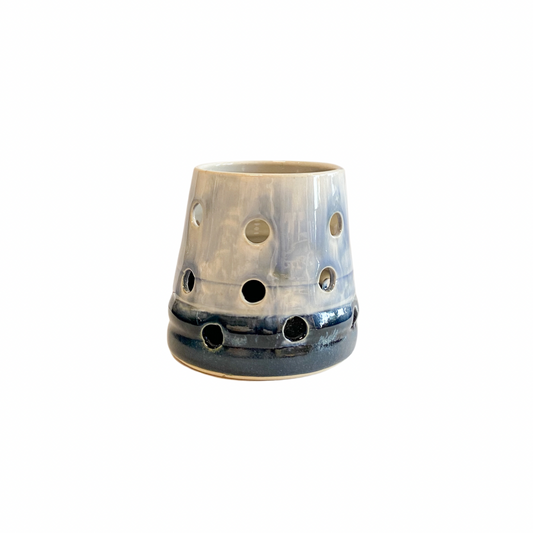 Hand thrown stoneware T light holder in graduated blue glaze and holes punched in it