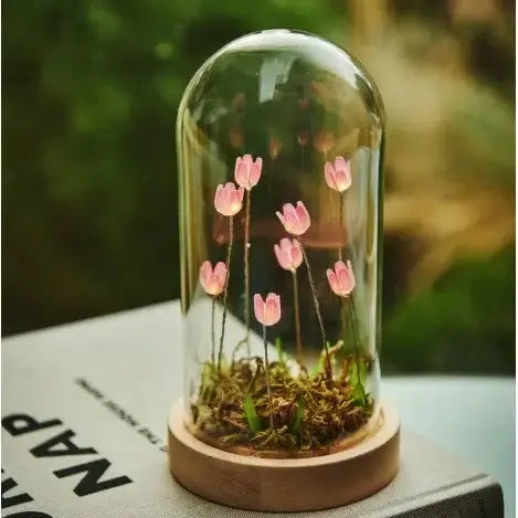 Glass dome with pink flowers on a book