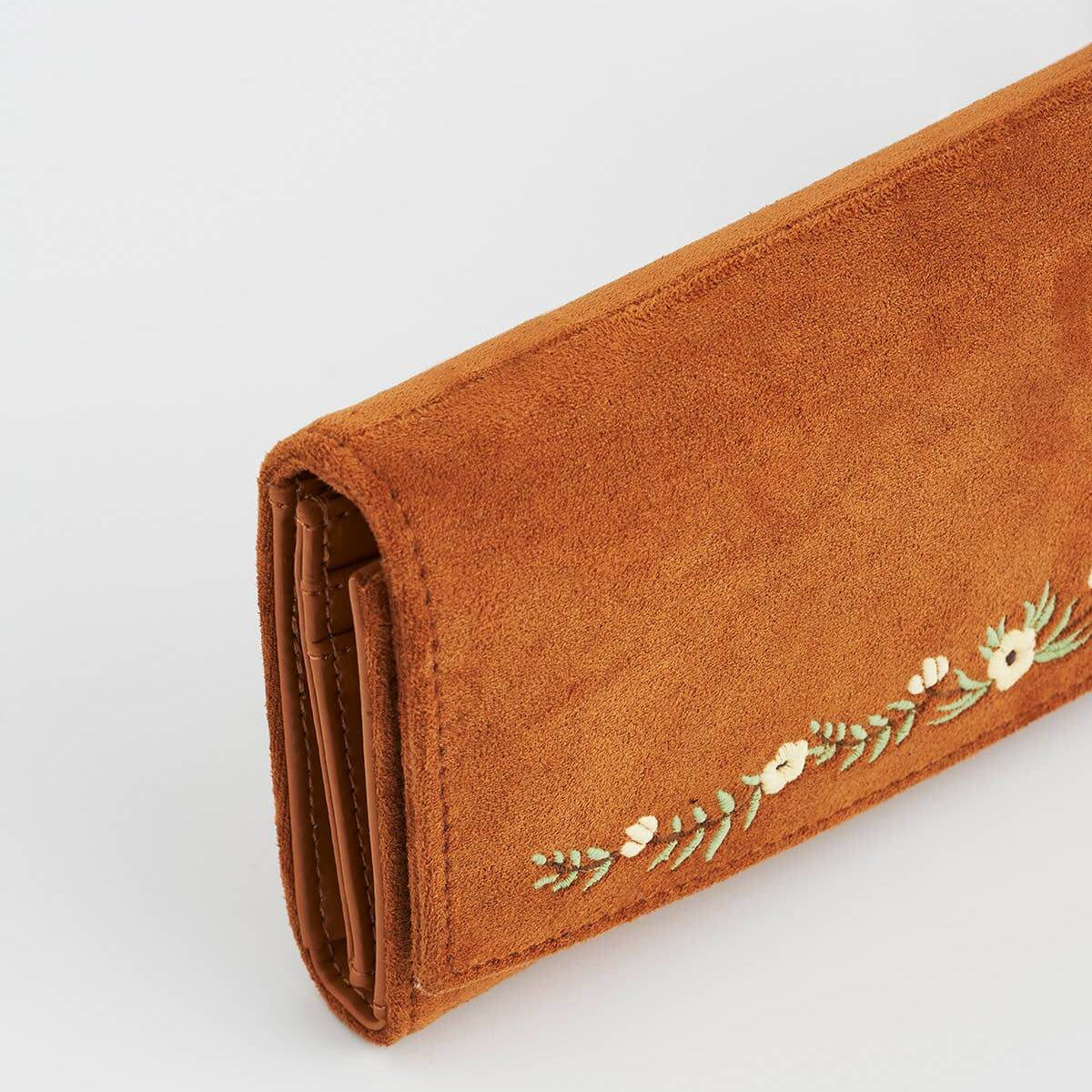 Brown wallet with floral embroidery on a light gray background