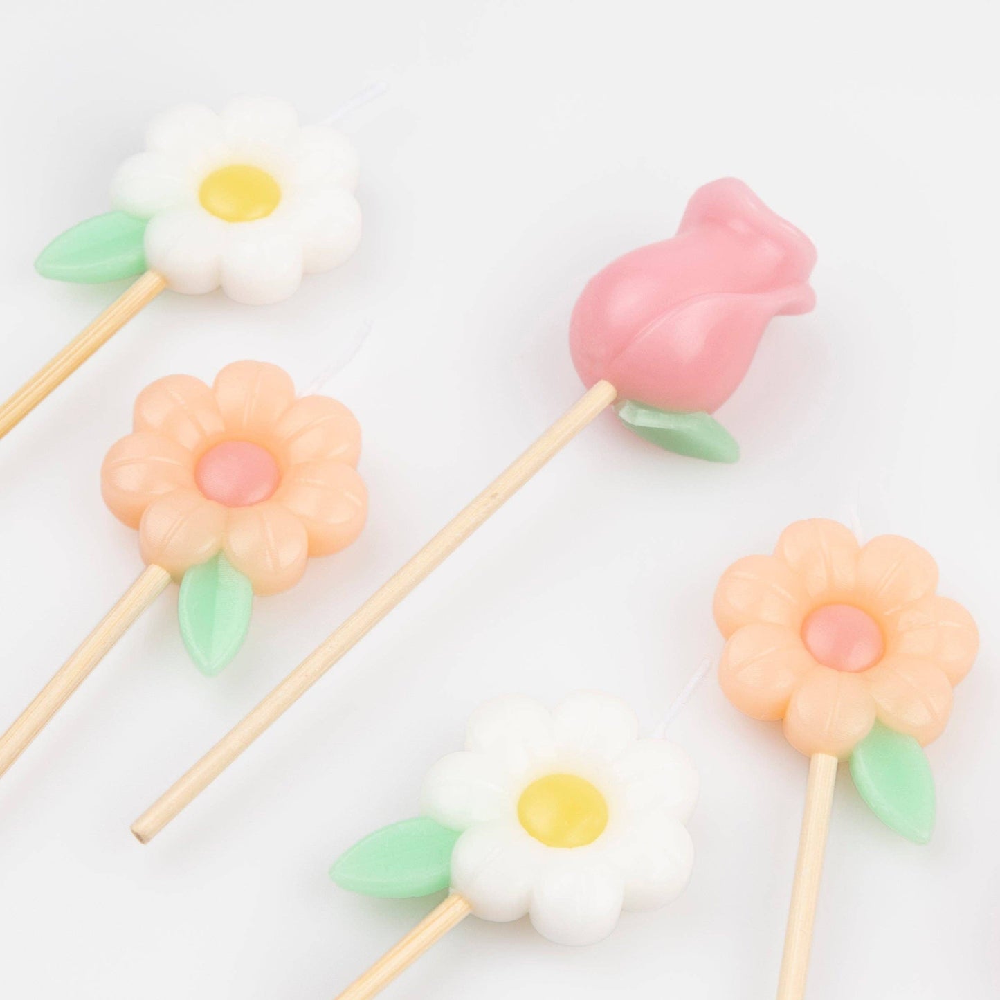 Pastel-colored flower-shaped lollipops on sticks against a white background