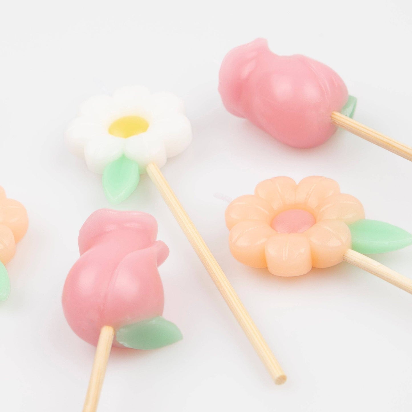 Pastel-colored flower-shaped lollipops on sticks against a white background
