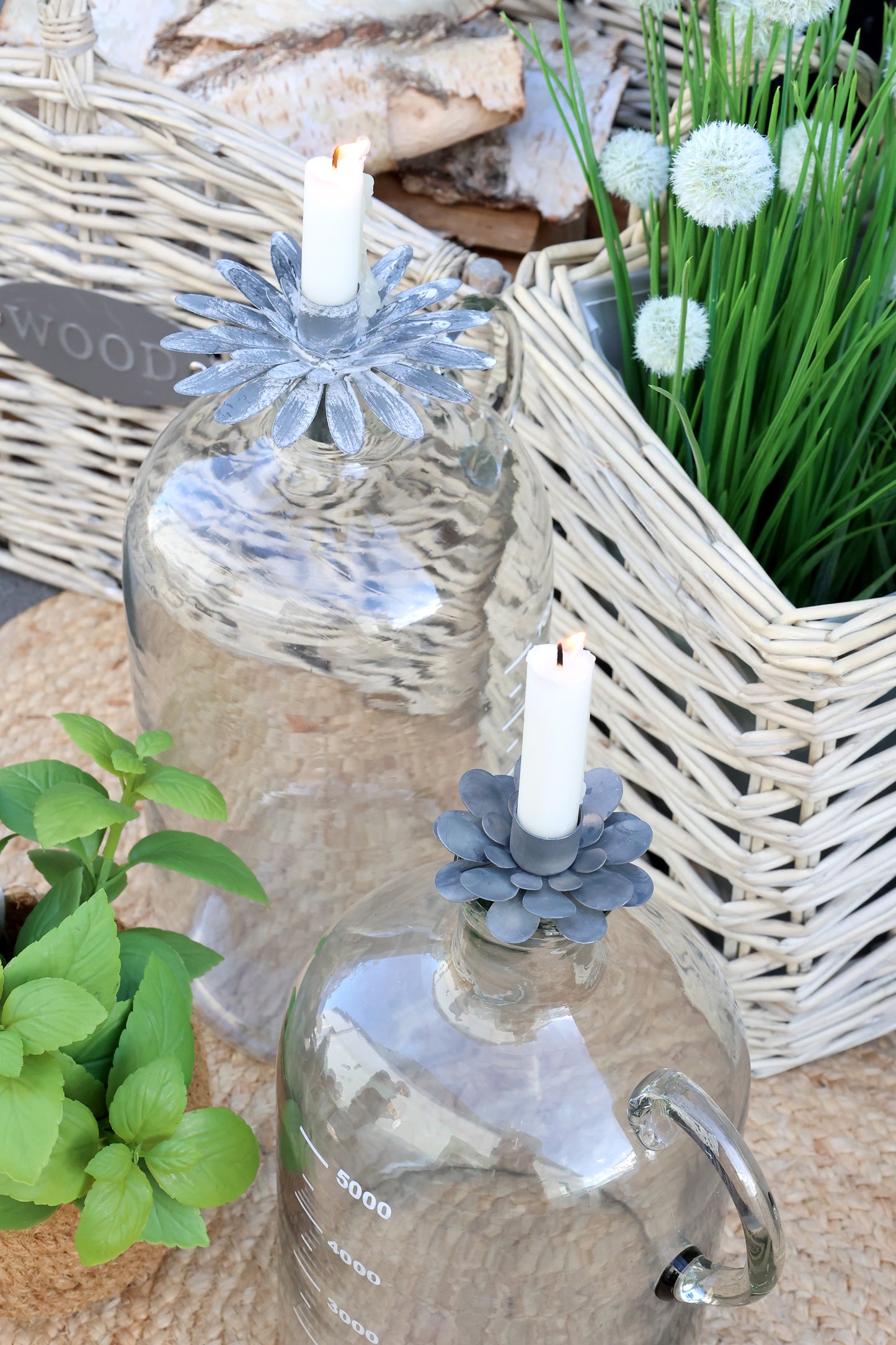 Decorative glass bottles with candles and floral arrangements on a textured surface.