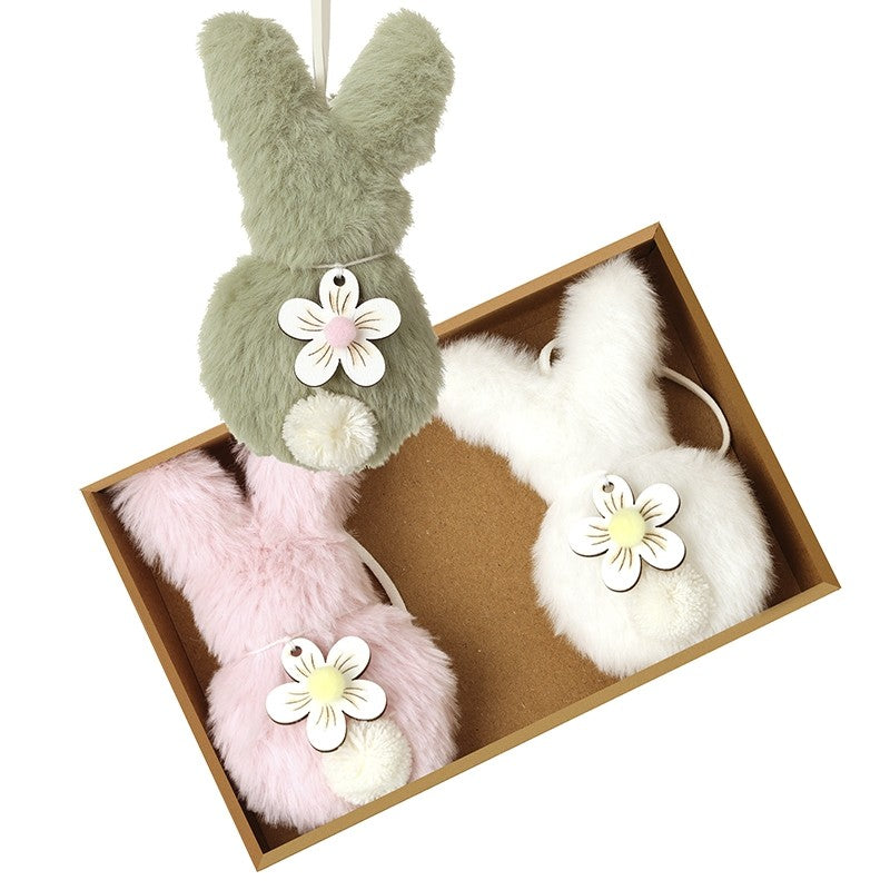 Set of plush bunny toys with flower decorations in a box on a white background