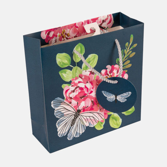 Floral and butterfly design on a blue gift bag with pink flowers and green leaves.
