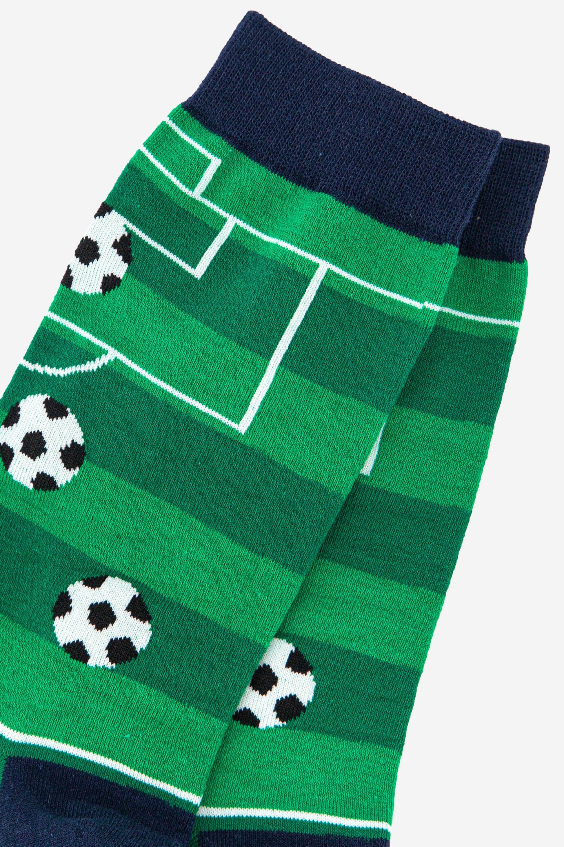 Green socks with soccer field design and black and white soccer balls on a gray background