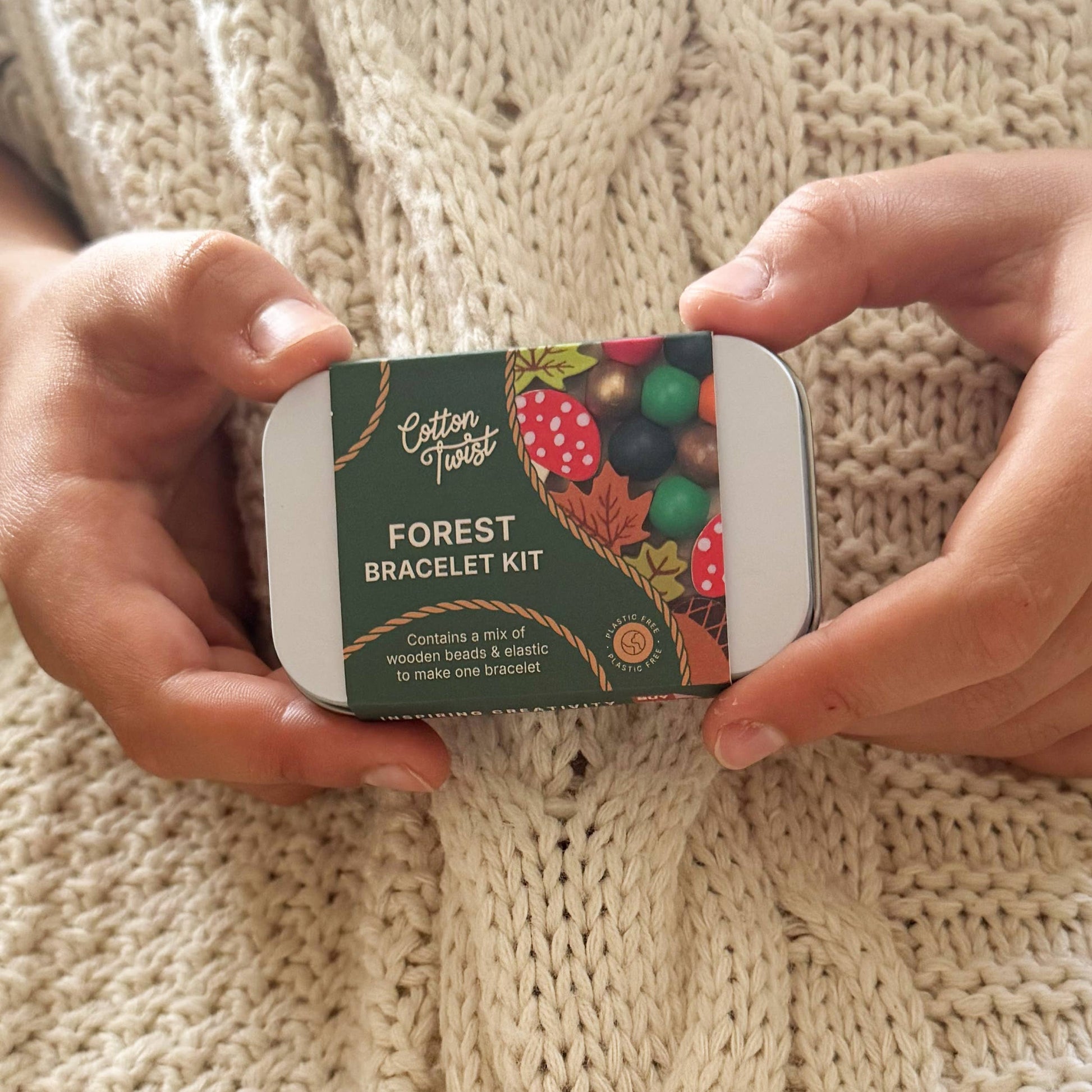 Cotton Twist Forest Bracelet Kit held by hands on a knitted fabric background