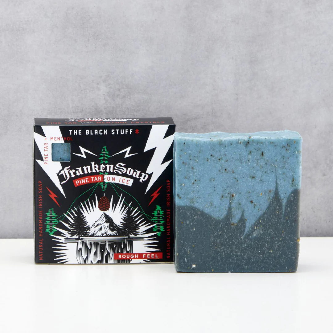 Bar of soap with packaging labeled 'The Black Stuff' by FrankenSoap on a gray background