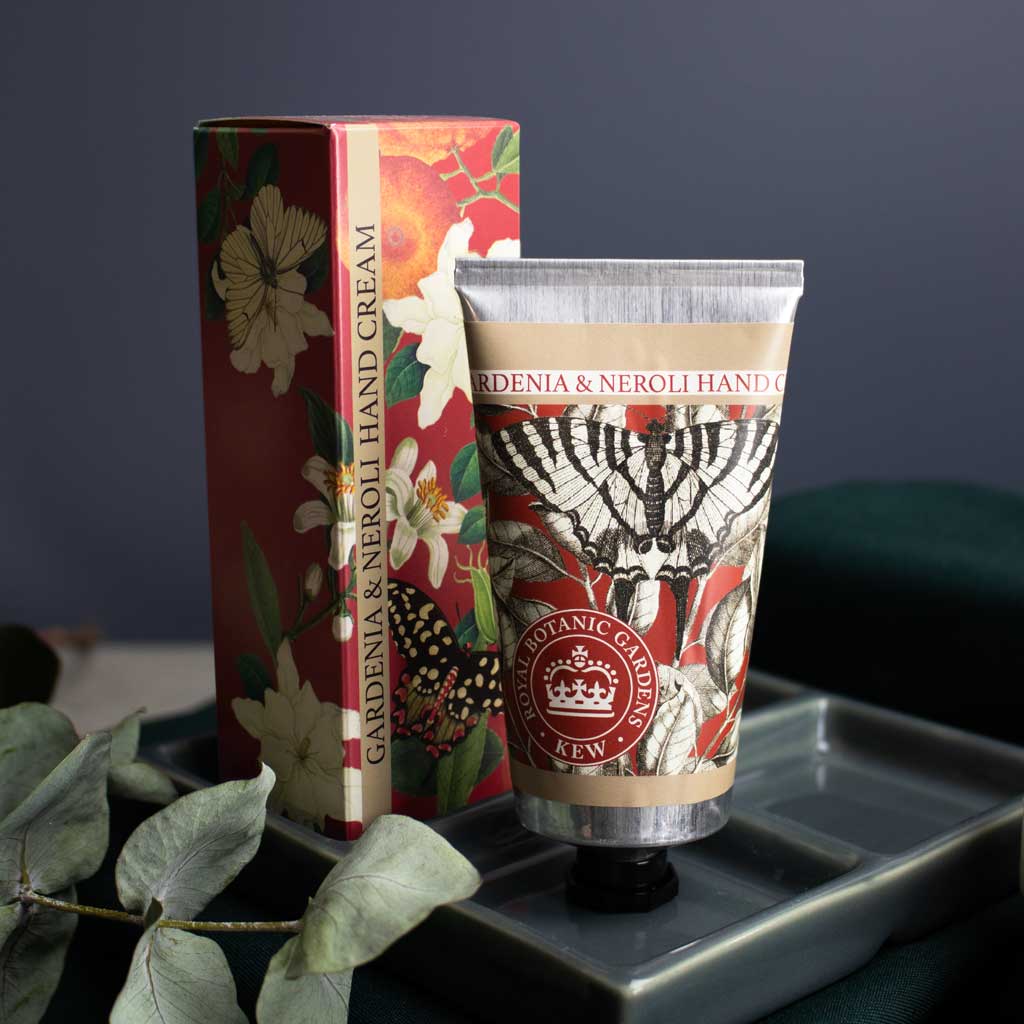 Hand cream and packaging with floral design on a dark surface