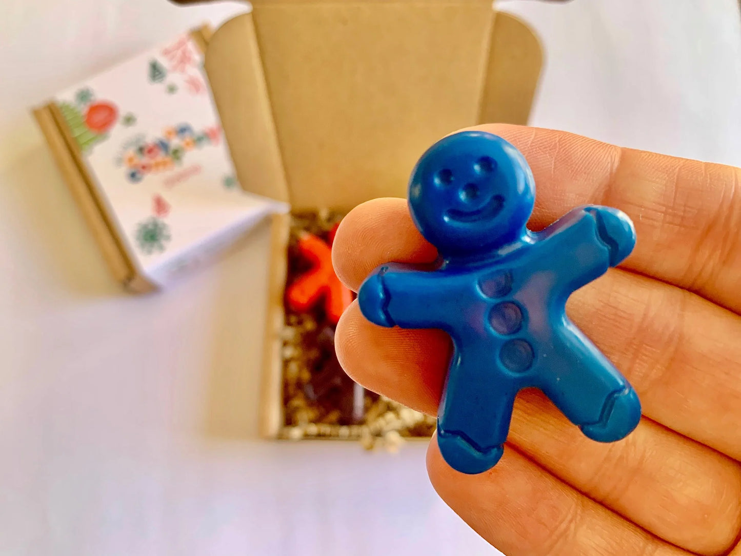 Blue gingerbread man crayon held in a hand with a blurred background