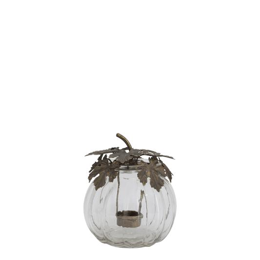 A clear glass pumpkin-shaped candle holder with a bronze metal leaf and stem decoration on top, containing a small tealight candle, shown against a plain white background.