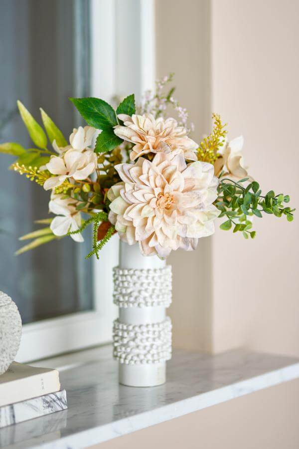 White textured vase with a bouquet of flowers on a surface