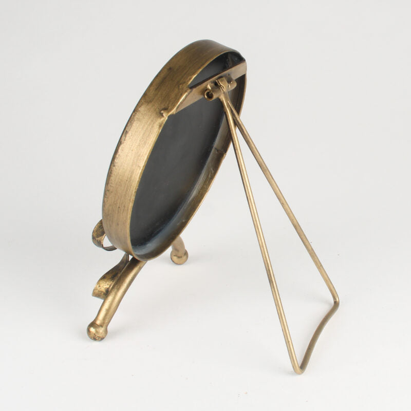 A vintage-style brass picture frame with a triangular metal stand, shown from an angled side view against a plain white background.