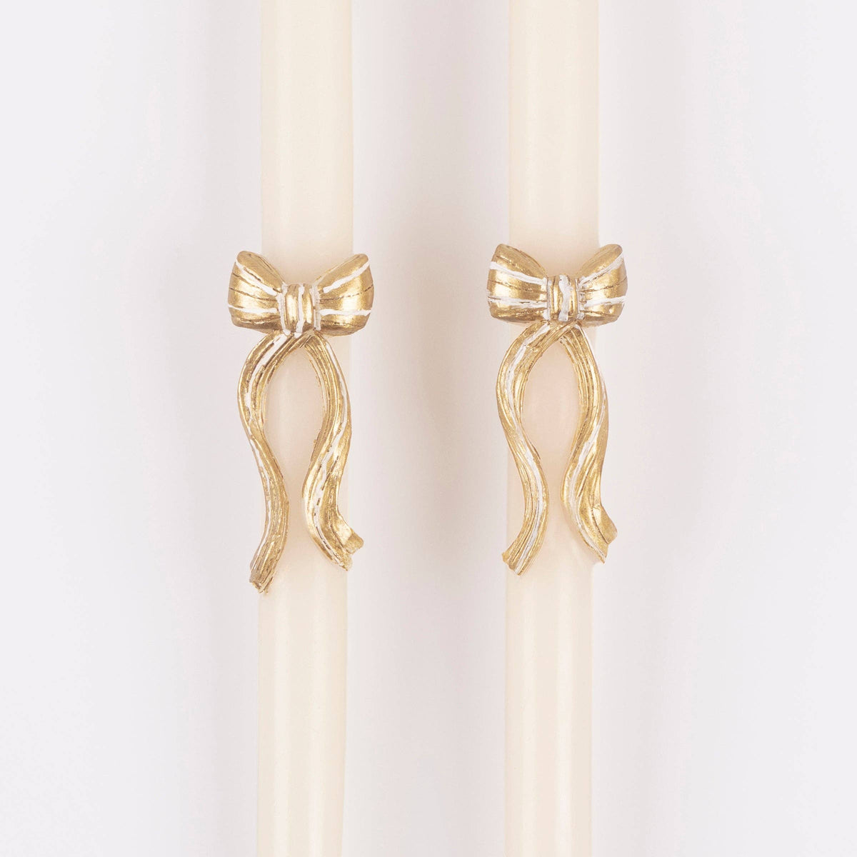 Close up view of two taper candles with gold bow detail