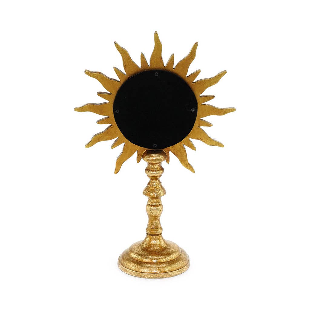 Decorative sun-shaped mirror on a stand with gold finish against a white background