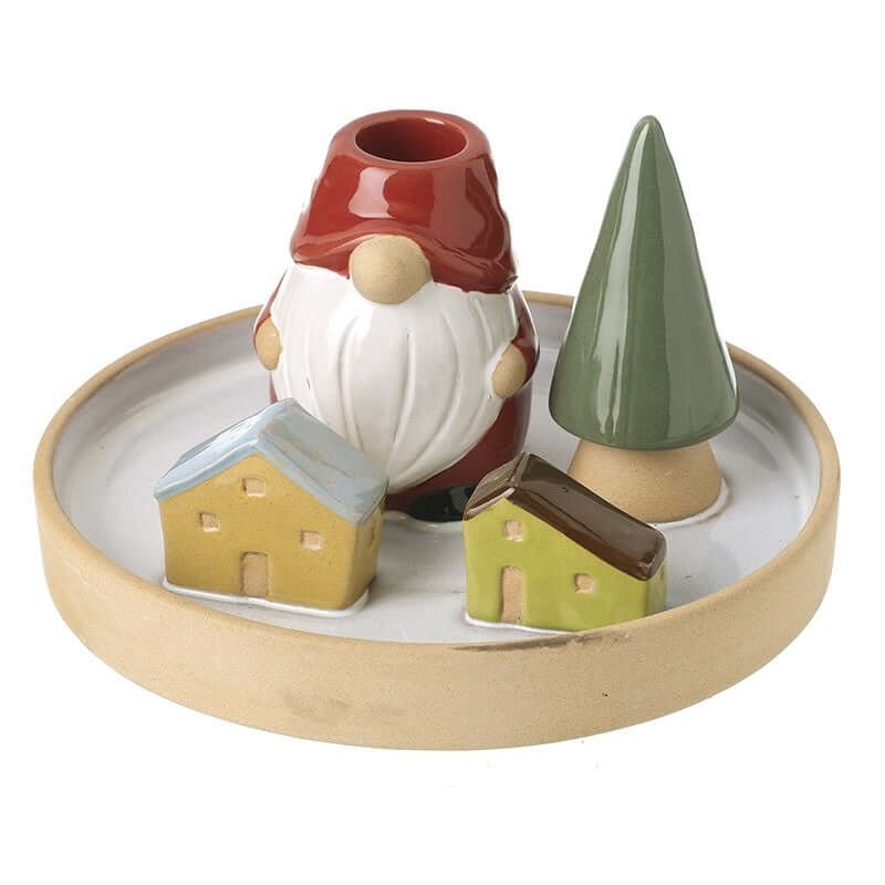 Decorative candle holder with a gnome, houses, and a tree on a round ceramic base.