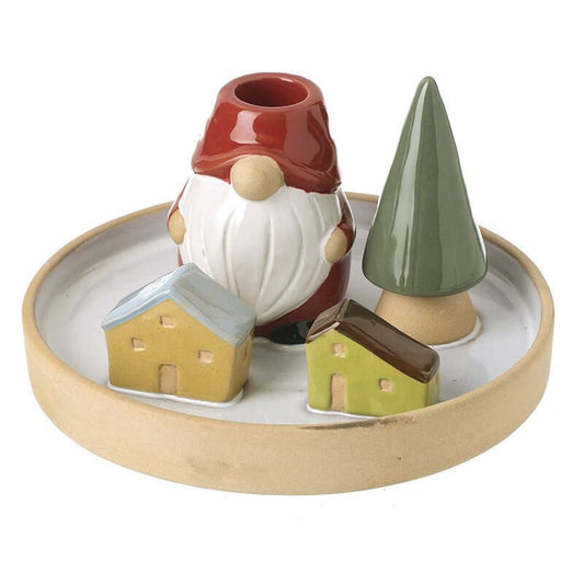 Decorative candle holder with a gnome, houses, and a tree on a round ceramic base.