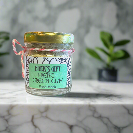 Jar of Eden's Gift French Green Clay Face Mask on a marble surface with a blurred plant background