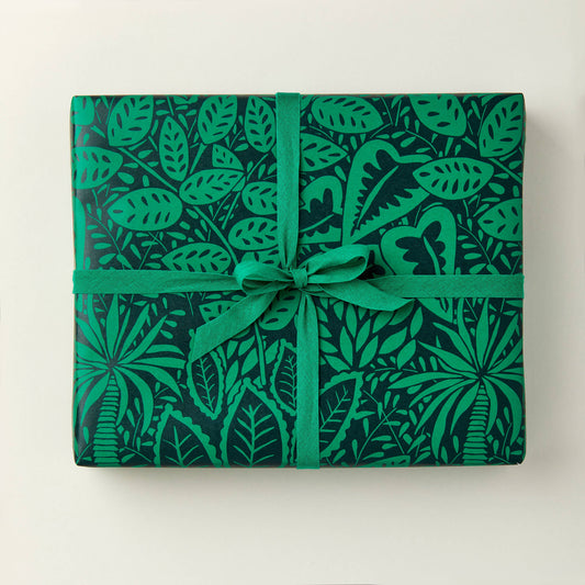 A sheet of green gift wrapping paper with a leaf pattern, tied with a green ribbon.