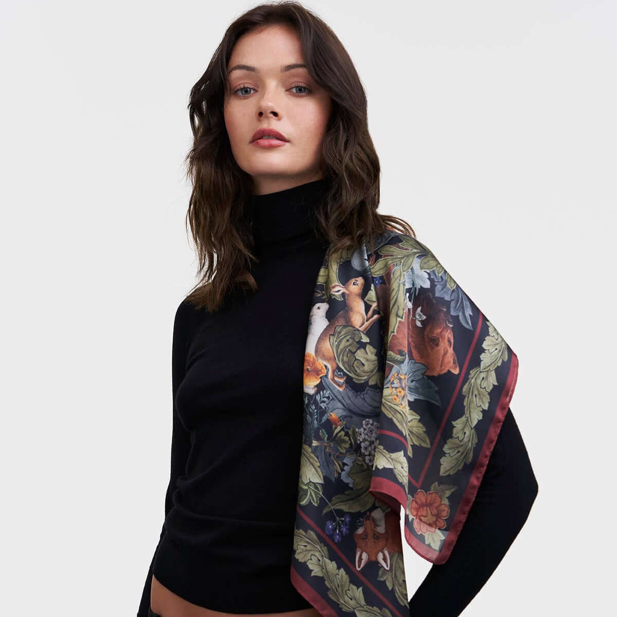 Woman wearing a black outfit with a patterned scarf on a white background