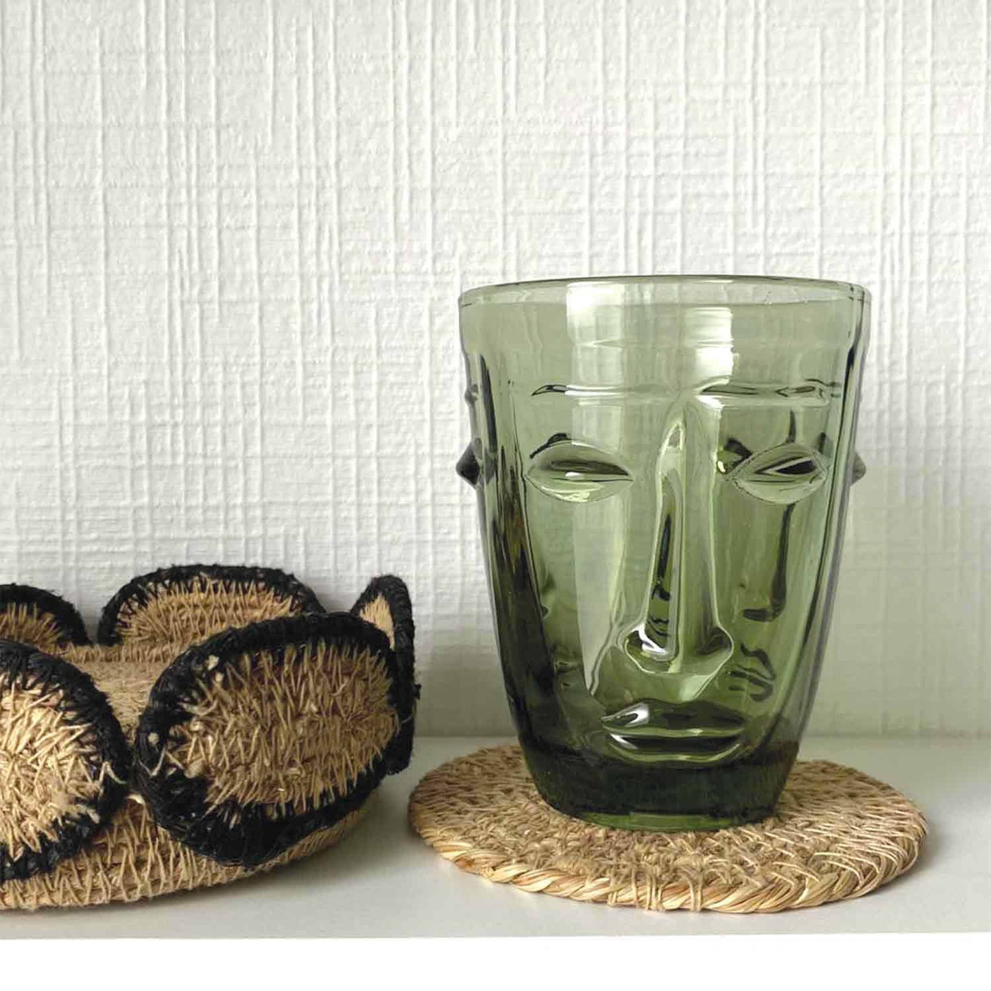 Clear drinking glass with face design on a table