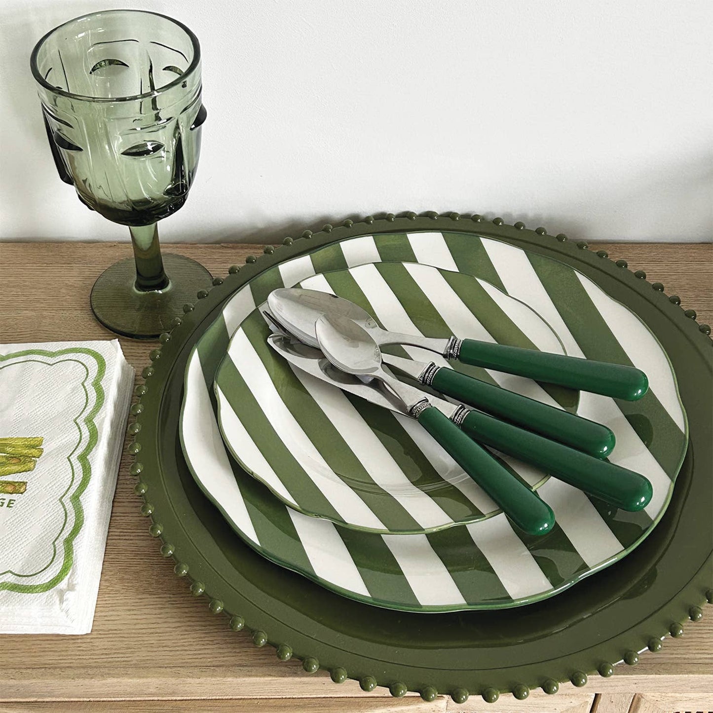 Green and white striped plates with cutlery on a wooden table