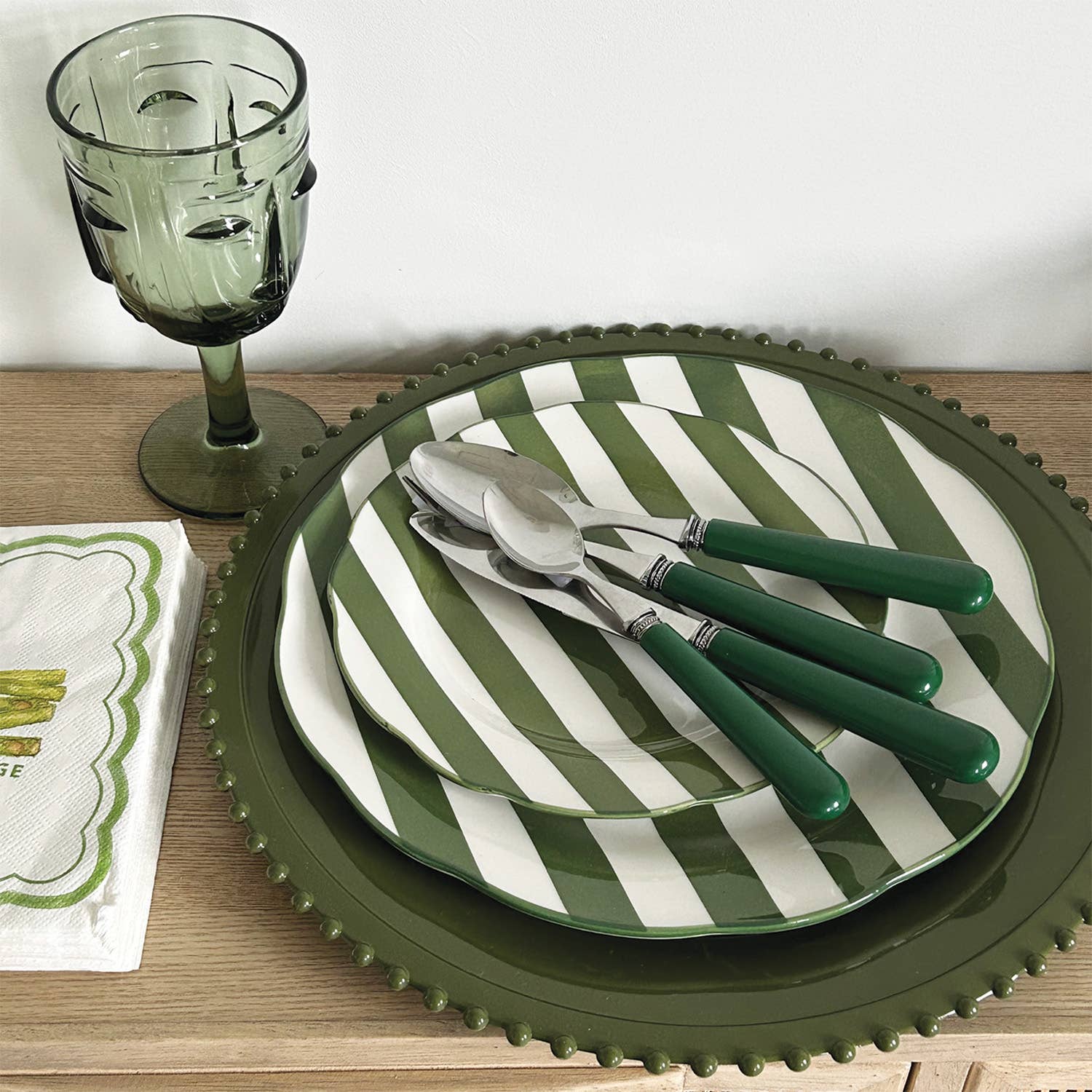 Green and white striped plates with cutlery on a wooden table