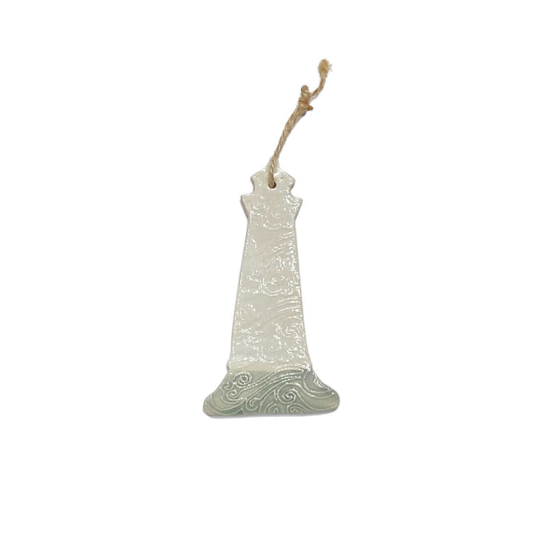 A ceramic lighthouse decoration with a white body, red base, and grey accents, hanging from a jute string.