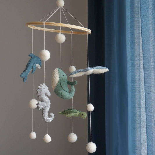Decorative mobile with sea-themed hanging toys against a neutral background