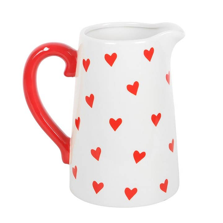 White pitcher with red hearts and a red handle on a white background