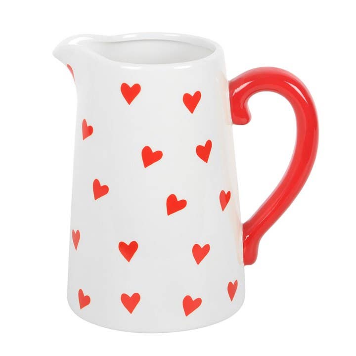 White pitcher with red heart pattern and red handle on a white background