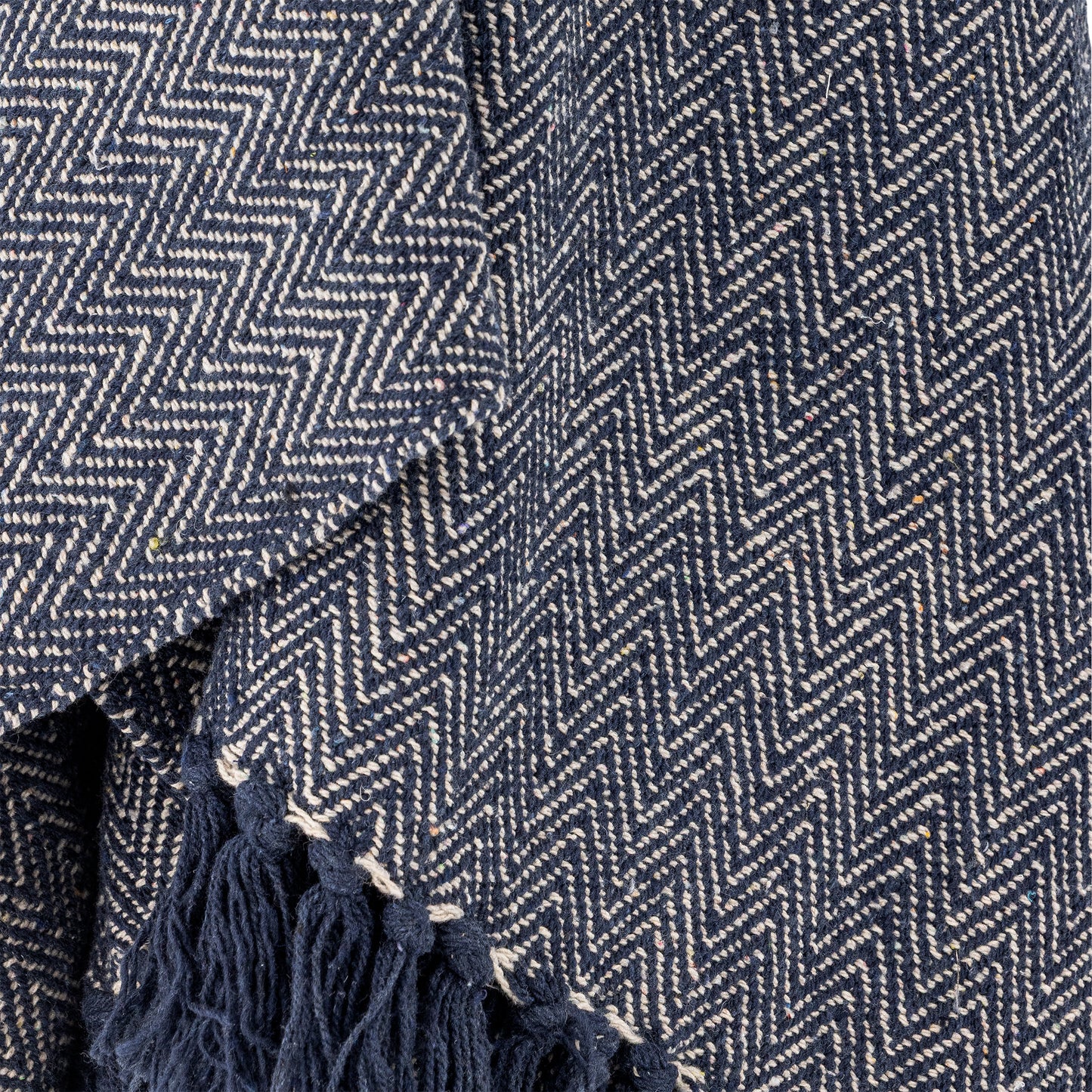 Close-up of a blue and white herringbone patterned fabric with tassels.